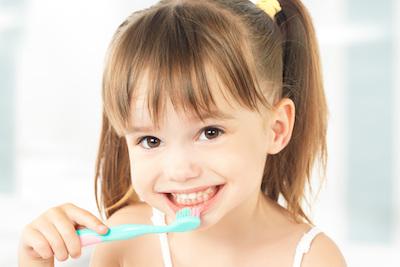 little girl brushing her teeth to prevent cavities