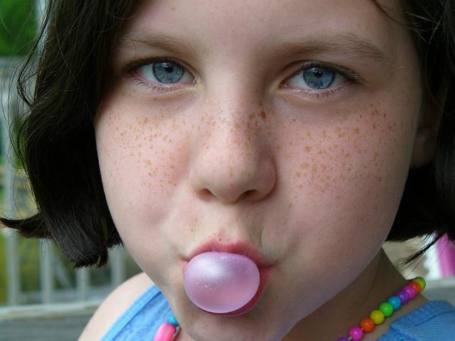 young girl blowing a bubble with gum