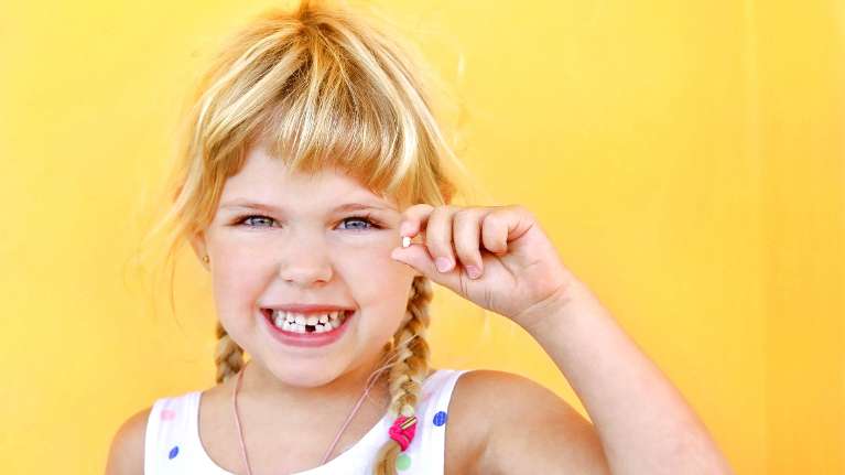 Young girl holding up lost tooth | Highlands Ranch Dentist