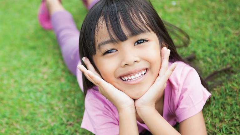 Young girl laying in grass in highlands ranch